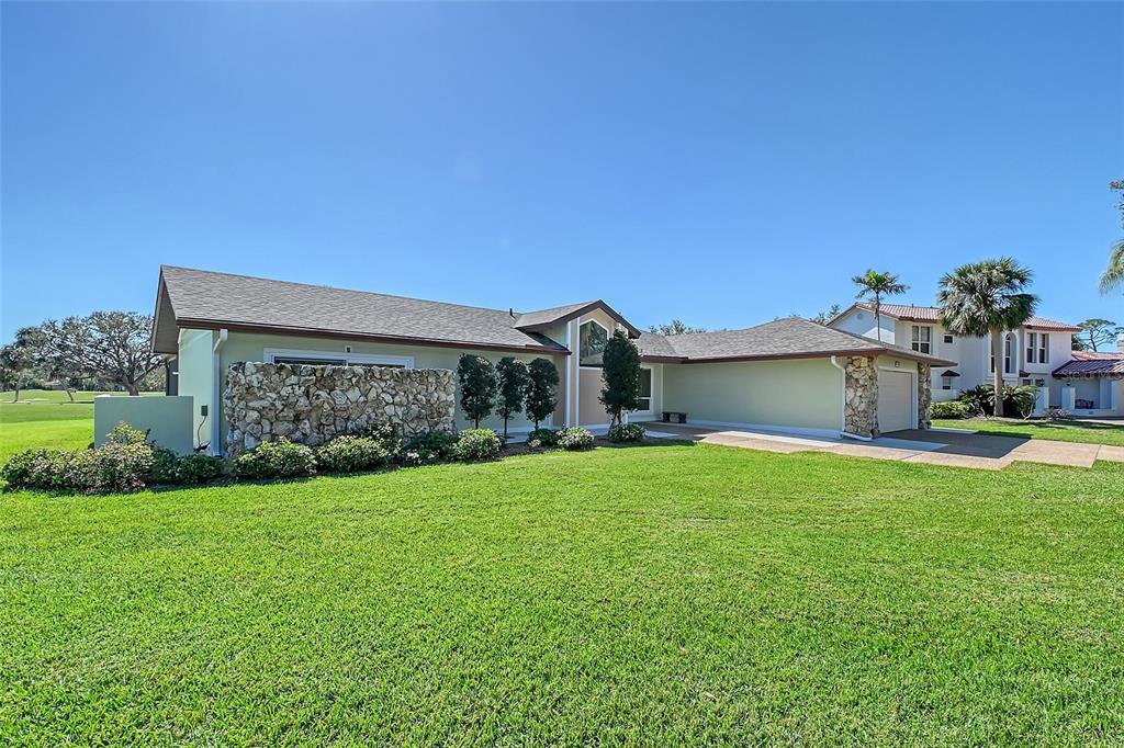 A single-story house with a stone facade, a shingled roof, and a green lawn — 3704 PRAIRIE DUNES DRIVE, SARASOTA, FL