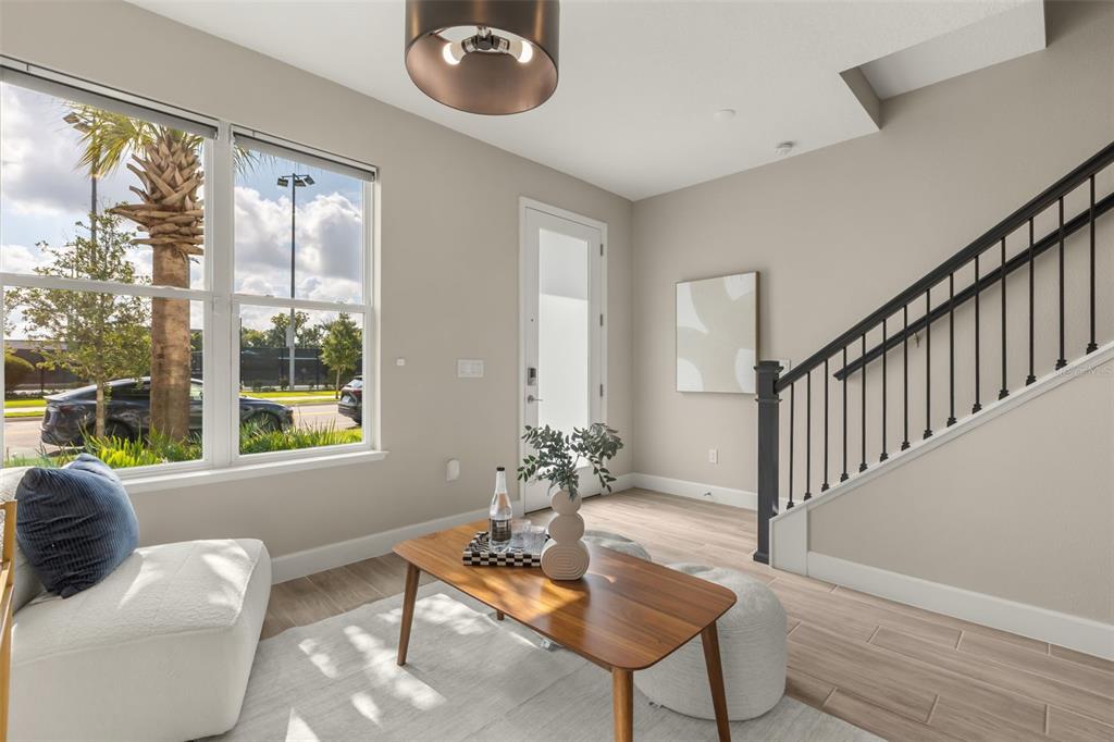 A modern living room features two white armchairs, a wooden coffee table, and two poufs — 2058 PACKING DISTRICT WAY, ORLANDO, FL