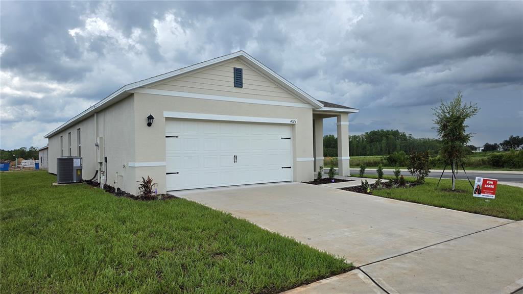 A single-story house with a two-car garage and a concrete driveway under a cloudy sky — 4075 LIMEKLIN FALLS LOOP, DAVENPORT, FL