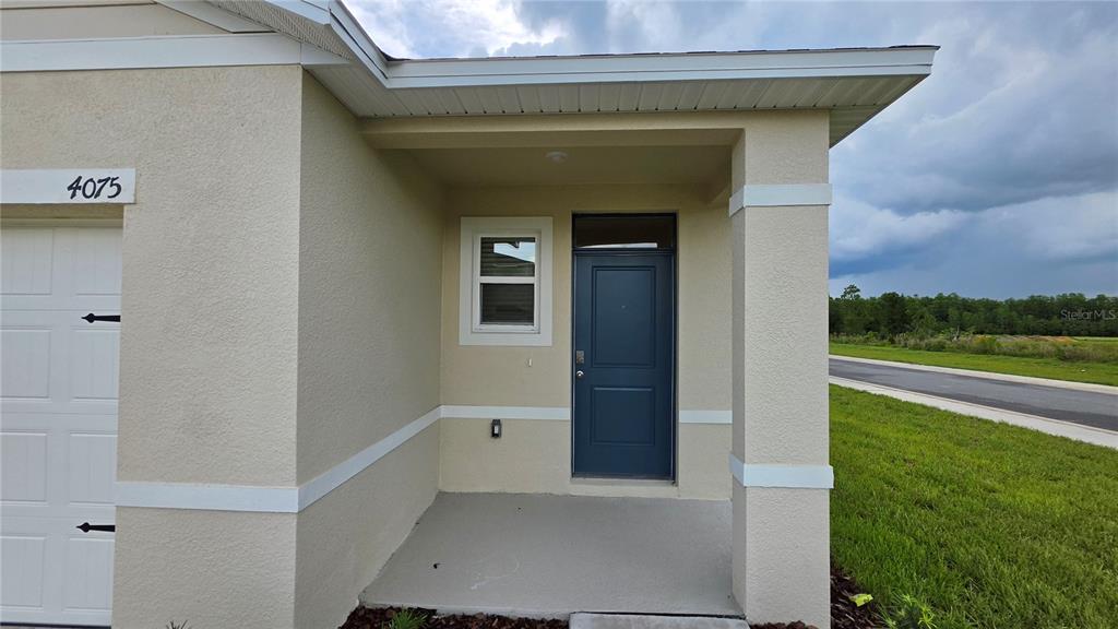 The exterior view shows a house entrance with a blue door, window, and concrete porch — 4075 LIMEKLIN FALLS LOOP, DAVENPORT, FL