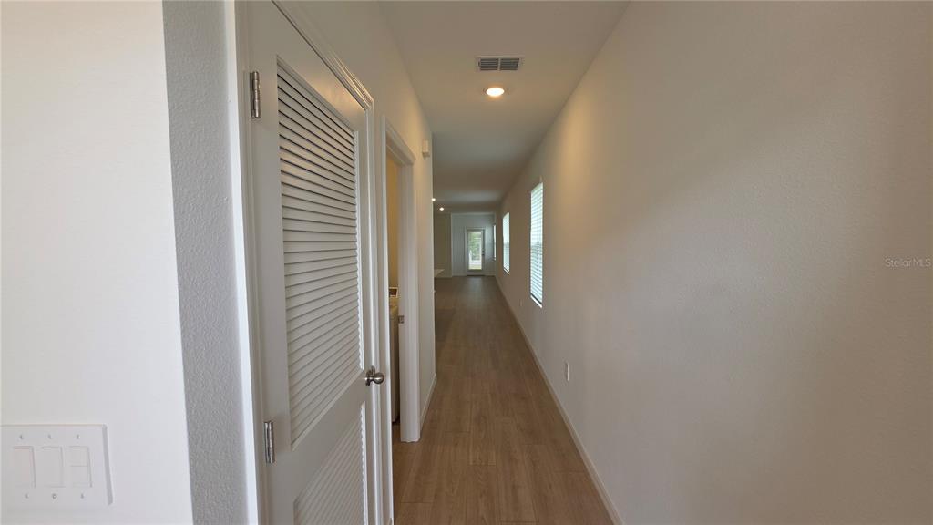 A long hallway with light wood-look flooring leads to a door at the far end — 4075 LIMEKLIN FALLS LOOP, DAVENPORT, FL