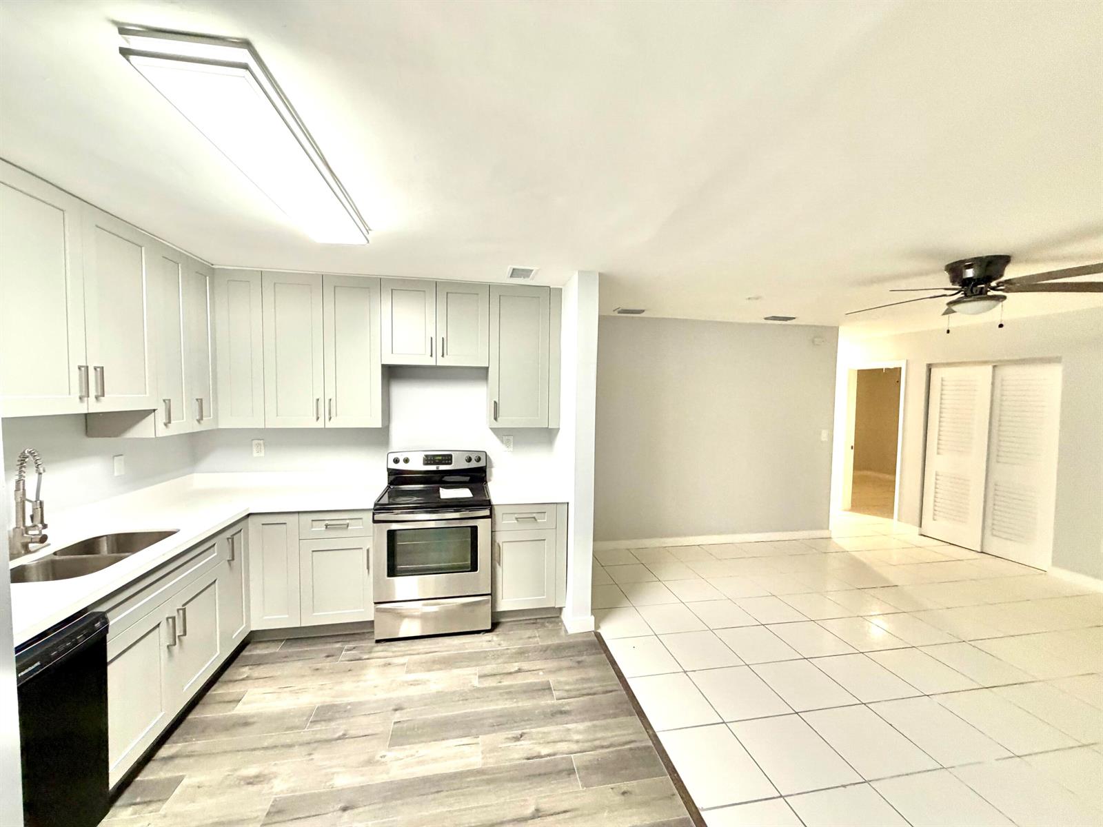 A kitchen with light gray cabinets and stainless steel appliances opens to a tiled room — 2941 NW 195th Street, Miami Gardens FL 33056, MIAMI GARDENS, FL