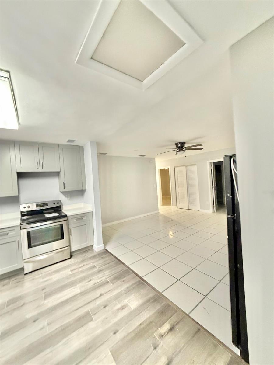A kitchen with light gray cabinets and stainless steel appliances transitions to a tiled dining area — 2941 NW 195th Street, Miami Gardens FL 33056, MIAMI GARDENS, FL