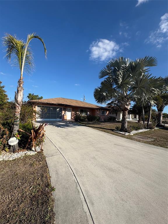A single-story house with a concrete driveway and palm trees under a clear blue sky — 321 VENETIA AVENUE, NORTH PORT, FL