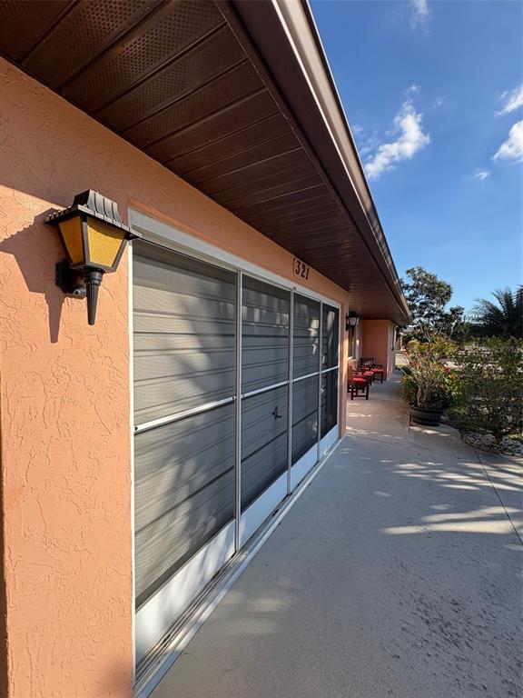 A peach-colored exterior wall features a sliding screen door and a wall-mounted lantern light — 321 VENETIA AVENUE, NORTH PORT, FL