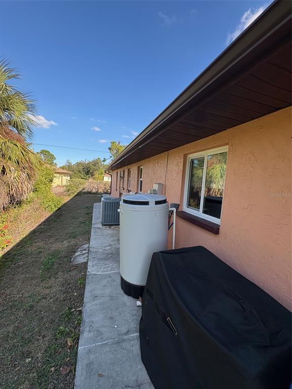 An exterior view of a house side featuring a water softener, HVAC unit, and grill — 321 VENETIA AVENUE, NORTH PORT, FL
