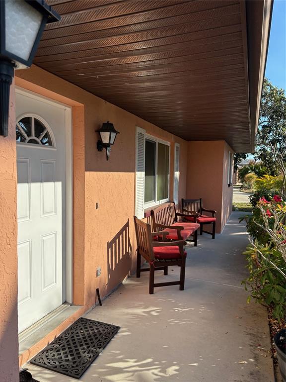 A covered porch features a white front door, two wooden chairs, and stucco walls — 321 VENETIA AVENUE, NORTH PORT, FL