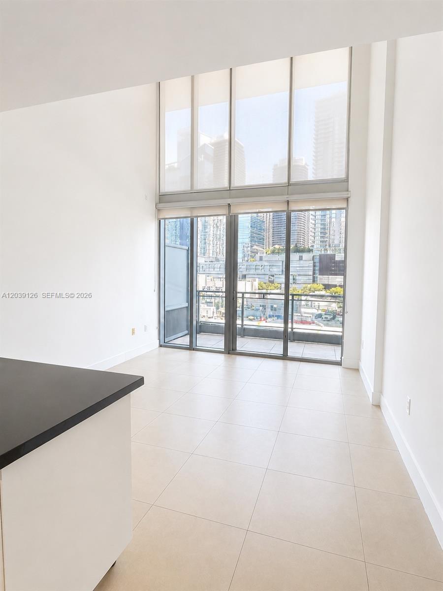 A bright living area features floor-to-ceiling windows, tile flooring, and access to a balcony — 92 SW 3rd St # 503, Miami FL 33130, MIAMI, FL