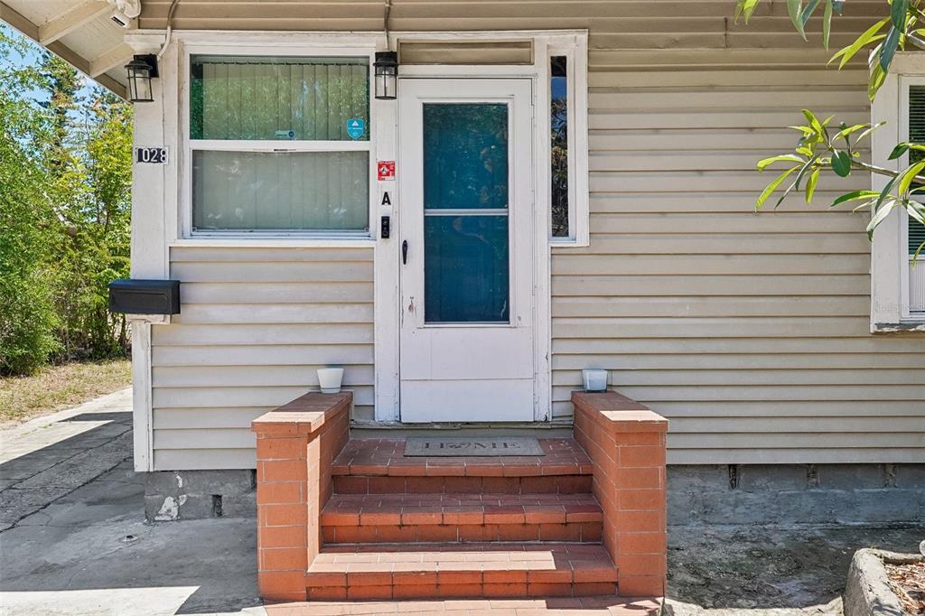 The exterior of a house features a white front door, brick steps, and horizontal siding — 1028 8TH AVENUE S, ST PETERSBURG, FL