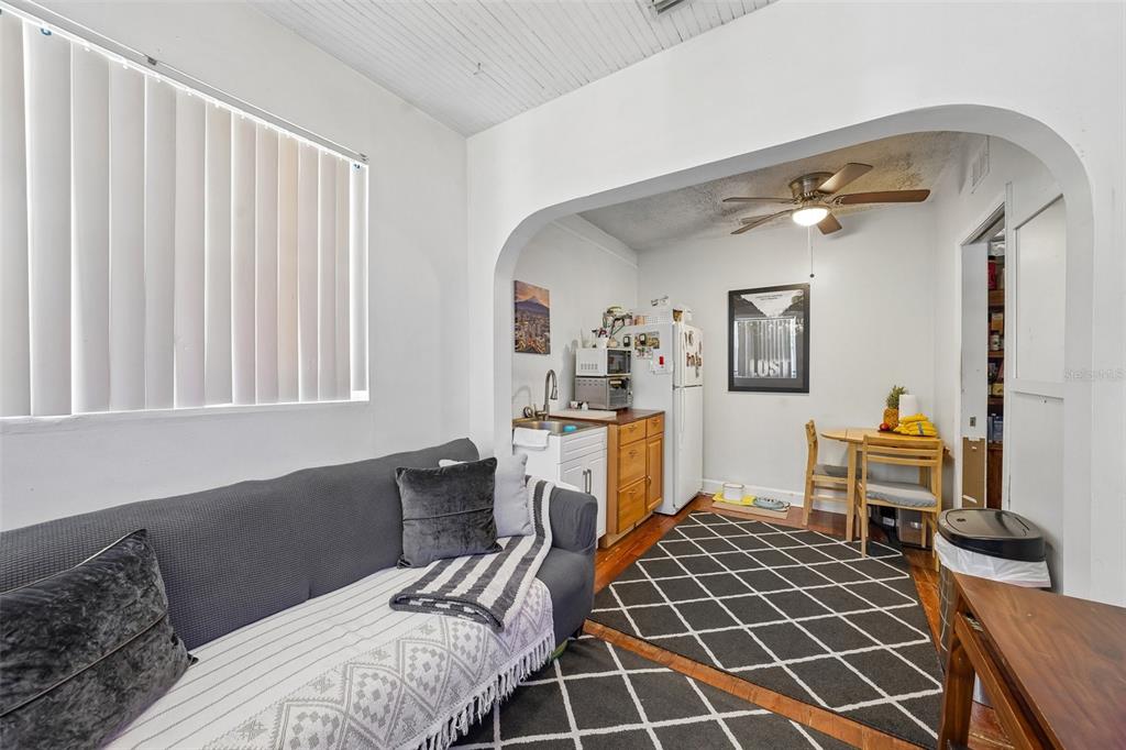 A living room with a grey sofa, a small kitchenette, and a dining area — 1028 8TH AVENUE S, ST PETERSBURG, FL
