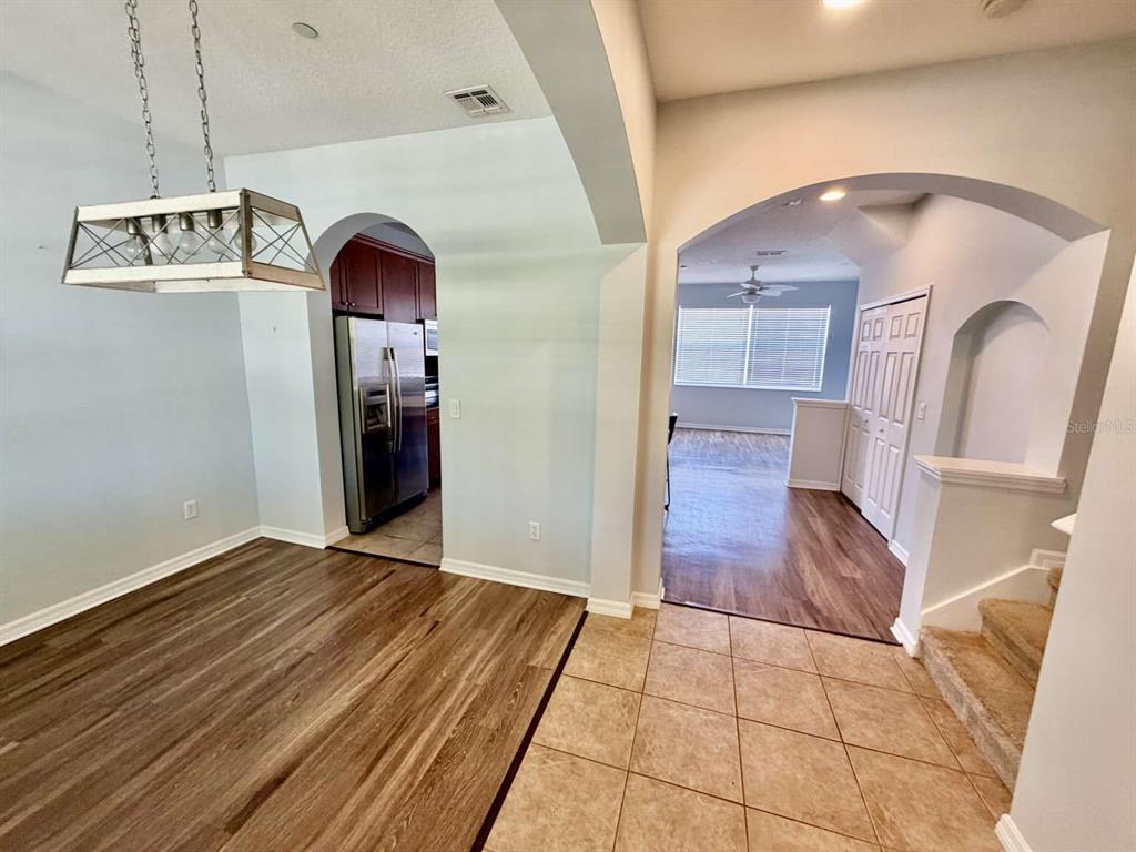 A dining area with wood-look flooring leads to a kitchen and a carpeted staircase — 9244 CARDINAL MEADOW TRAIL, ORLANDO, FL