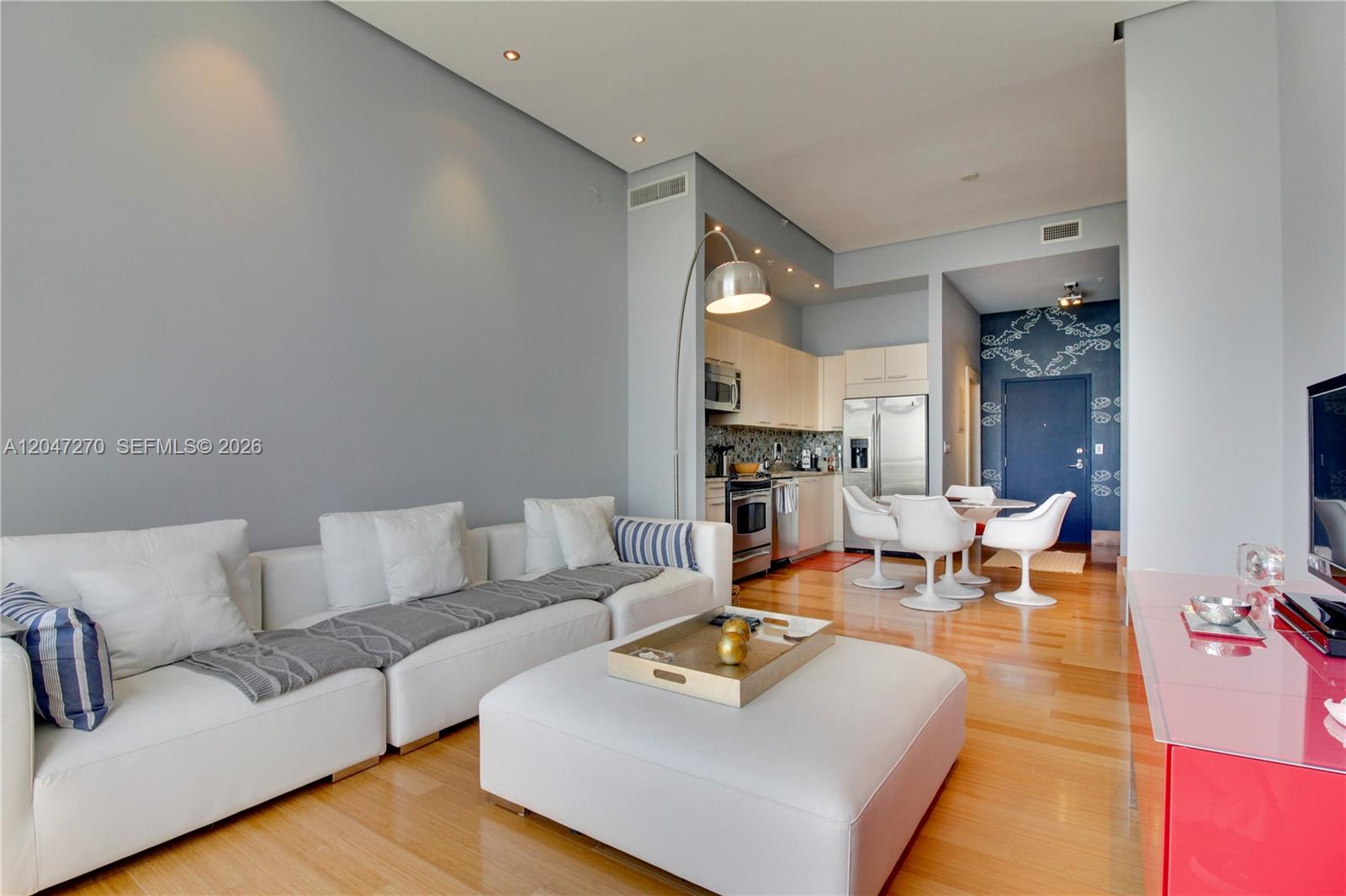 A modern living room and kitchen area with white furniture, hardwood floors, and blue walls — 2001 Meridian Ave # 21, Miami Beach FL 33139, MIAMI BEACH, FL