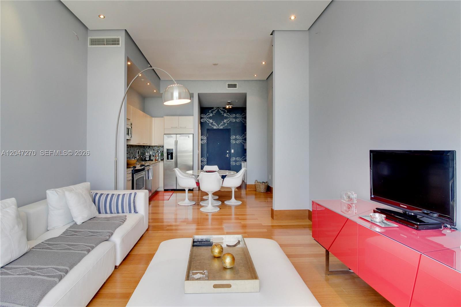 A living room with a white sofa, red media console, and an adjacent kitchen area — 2001 Meridian Ave # 21, Miami Beach FL 33139, MIAMI BEACH, FL