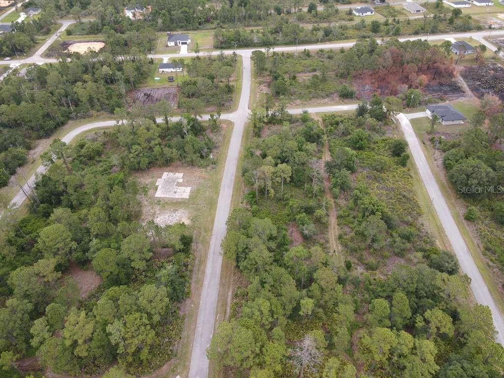 An aerial view shows a paved road intersecting a wooded area with several residential lots — 5044 PUEBLO AVENUE, SEBRING, FL