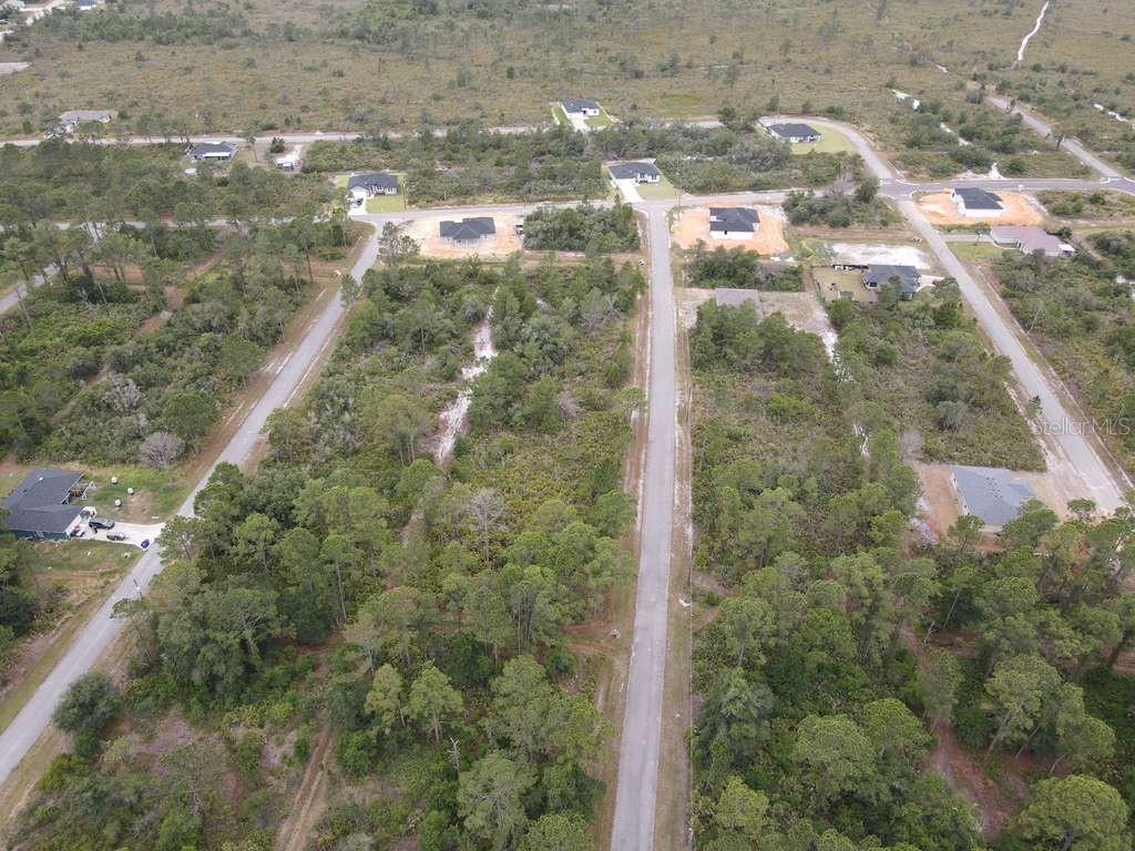 An aerial view shows a paved road winding through a wooded area with scattered houses — 5044 PUEBLO AVENUE, SEBRING, FL