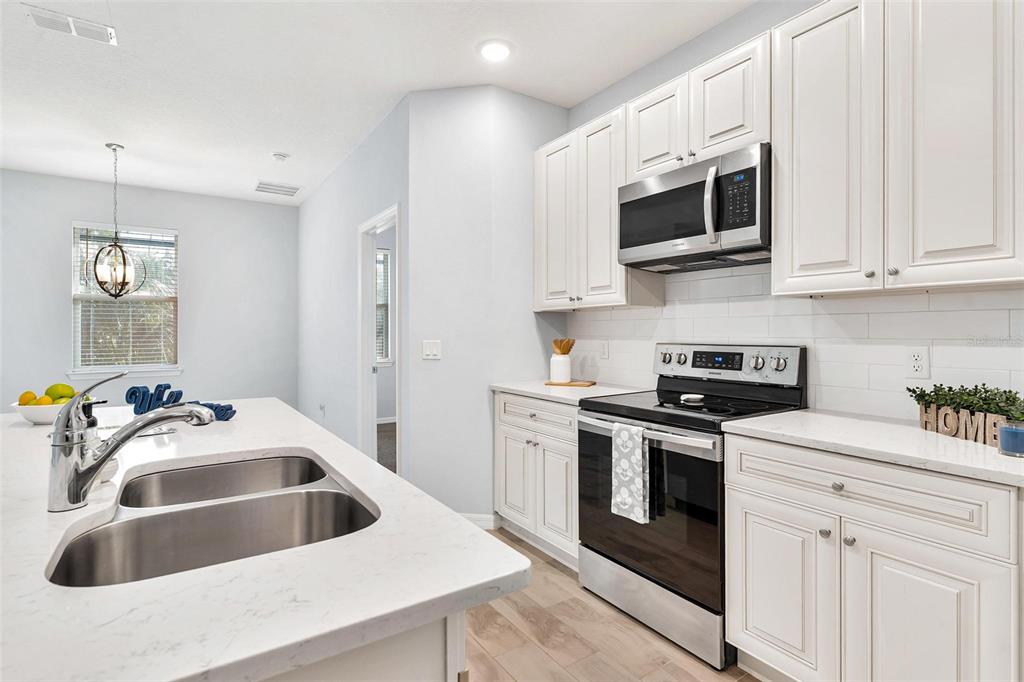 A paved patio features a covered fire pit, a wooden privacy fence, and surrounding landscaping — 944 BELLE OAK DRIVE, LEESBURG, FL