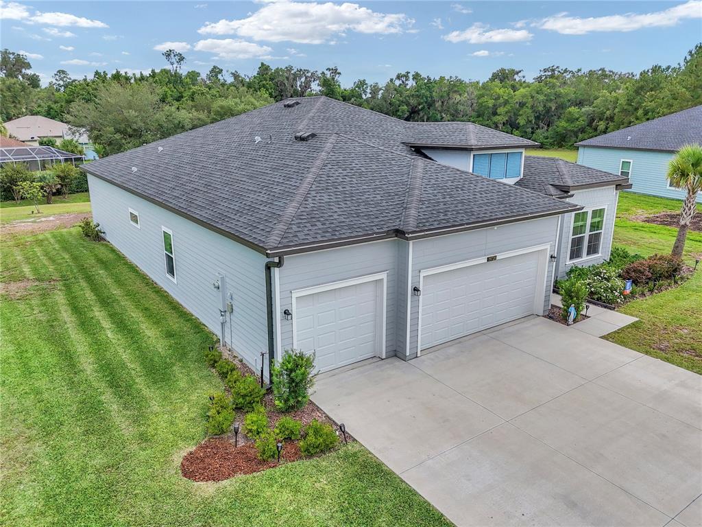 An aerial view of a light blue house with a three-car garage and shingled roof — 19720 SW 79TH PLACE, DUNNELLON, FL