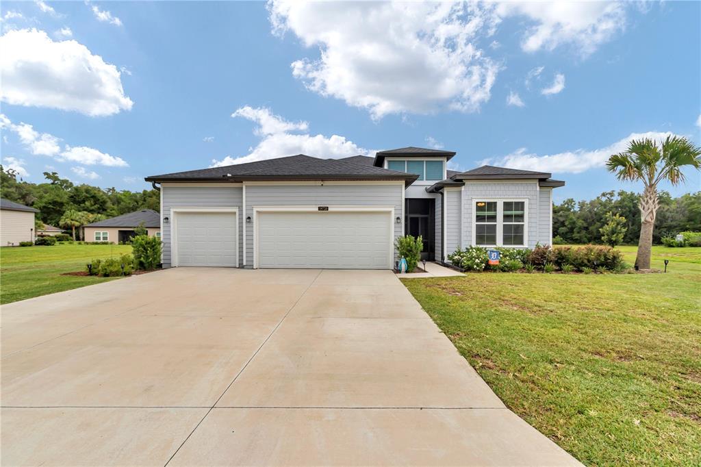 A light blue single-story house with a three-car garage and a concrete driveway — 19720 SW 79TH PLACE, DUNNELLON, FL