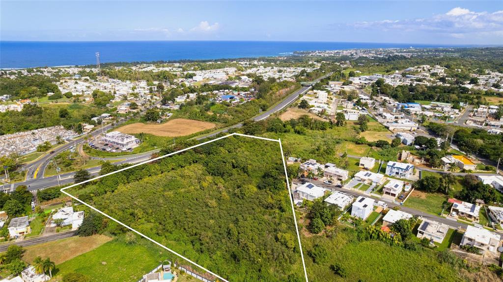 An aerial view shows a large, undeveloped plot of land outlined in white near houses — CARR. NUM. 2 KM. 91.8, CAMUY, PR