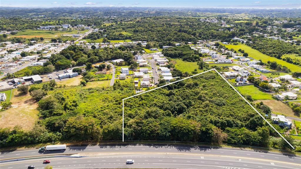 An aerial view shows a large, undeveloped plot of land adjacent to a multi-lane highway — CARR. NUM. 2 KM. 91.8, CAMUY, PR