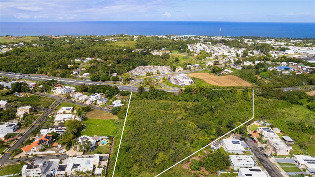 An aerial view shows a large, undeveloped plot of land bordered by residential neighborhoods and highways — CARR. NUM. 2 KM. 91.8, CAMUY, PR