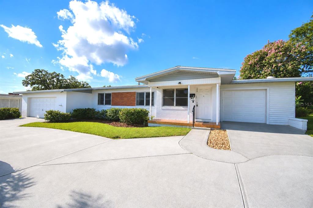 A single-story white house with a brick accent, two garages, and a concrete driveway — 906 AVENUE M SE, WINTER HAVEN, FL