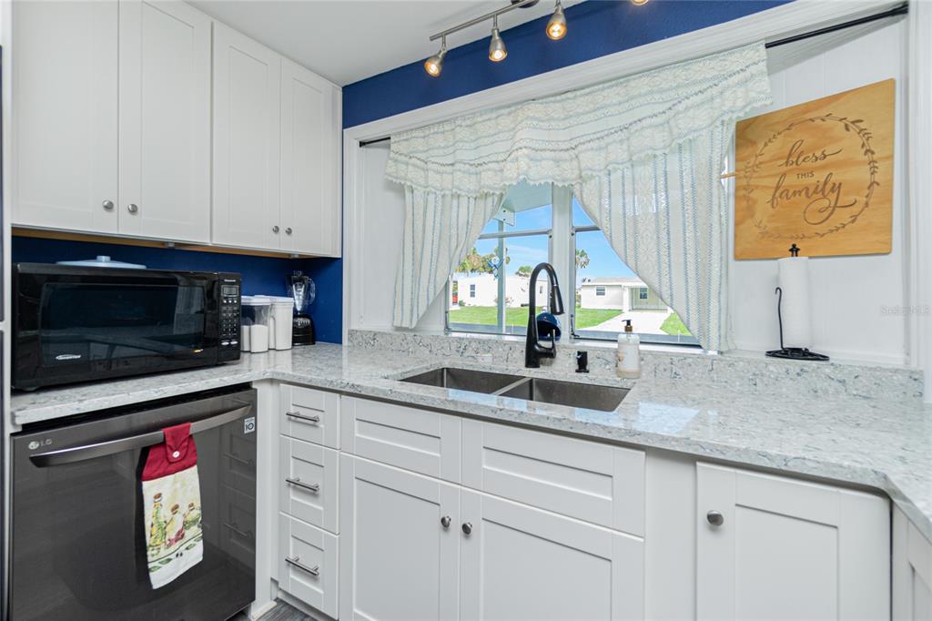 A kitchen features white cabinets, granite countertops, a double sink, and a black microwave — 1520 BLUE HERON DRIVE, ENGLEWOOD, FL