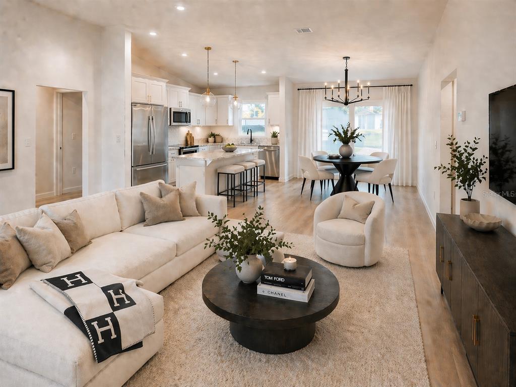 This rendering shows an open-concept living room, dining area, and kitchen with light wood floors — 11081 SW 107TH PLACE, DUNNELLON, FL