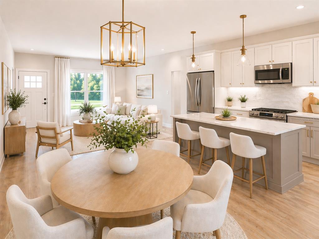 An open-concept kitchen, dining area, and living room featuring light wood floors and white cabinetry — 11081 SW 107TH PLACE, DUNNELLON, FL