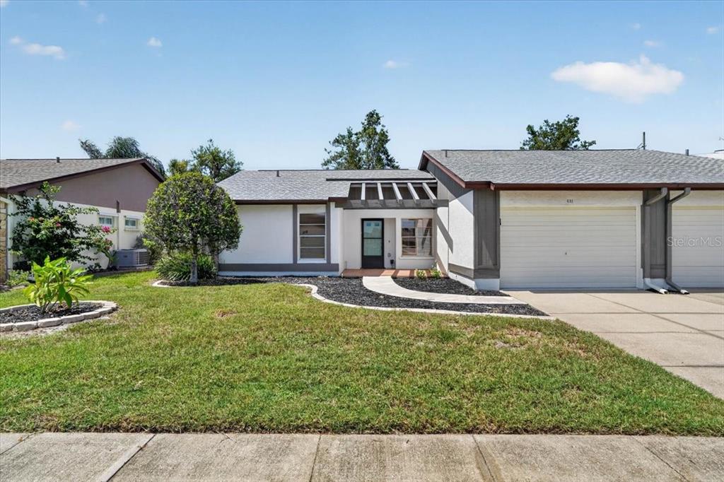 A single-story house with a white stucco exterior, a two-car garage, and a front lawn — 631 FOXWOOD BOULEVARD UNIT 256, ENGLEWOOD, FL