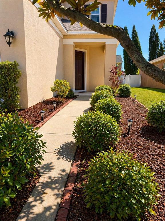 A concrete walkway leads to the front door of a house with landscaped garden beds — 8623 DEEP MAPLE DRIVE, RIVERVIEW, FL