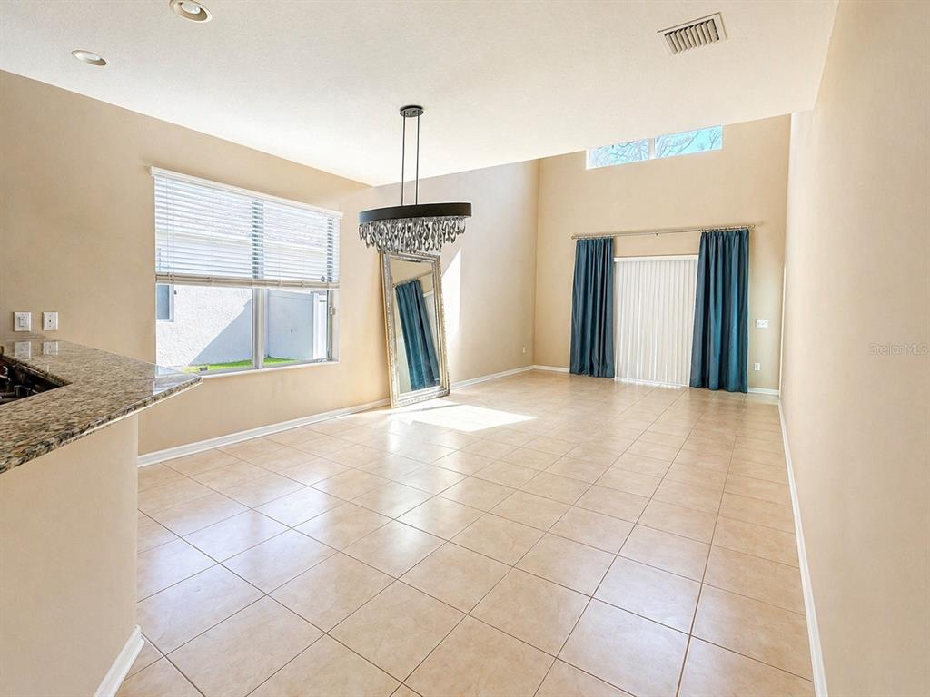 A spacious dining area with tile floors, a large chandelier, and a tall floor mirror — 8623 DEEP MAPLE DRIVE, RIVERVIEW, FL