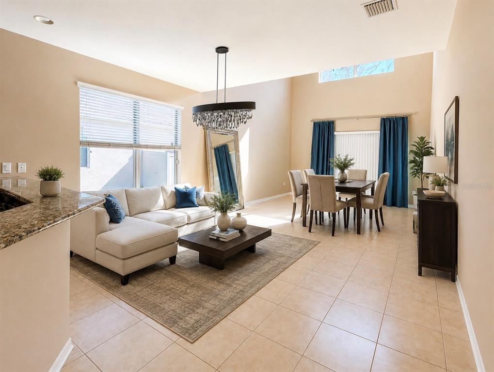 An open-concept living and dining area features tile flooring, a sectional sofa, and high ceilings — 8623 DEEP MAPLE DRIVE, RIVERVIEW, FL