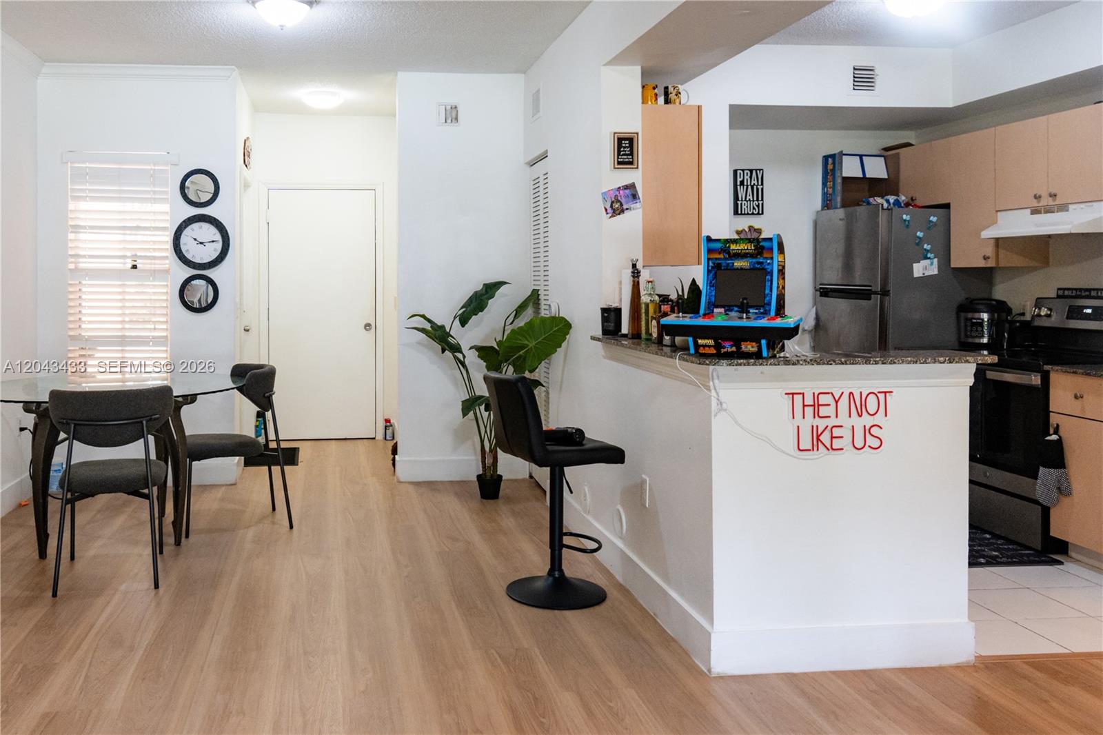 A dining area and kitchen feature light wood flooring, a breakfast bar, and modern decor — 2482 Centergate Dr # 104, Miramar FL 33025, MIRAMAR, FL