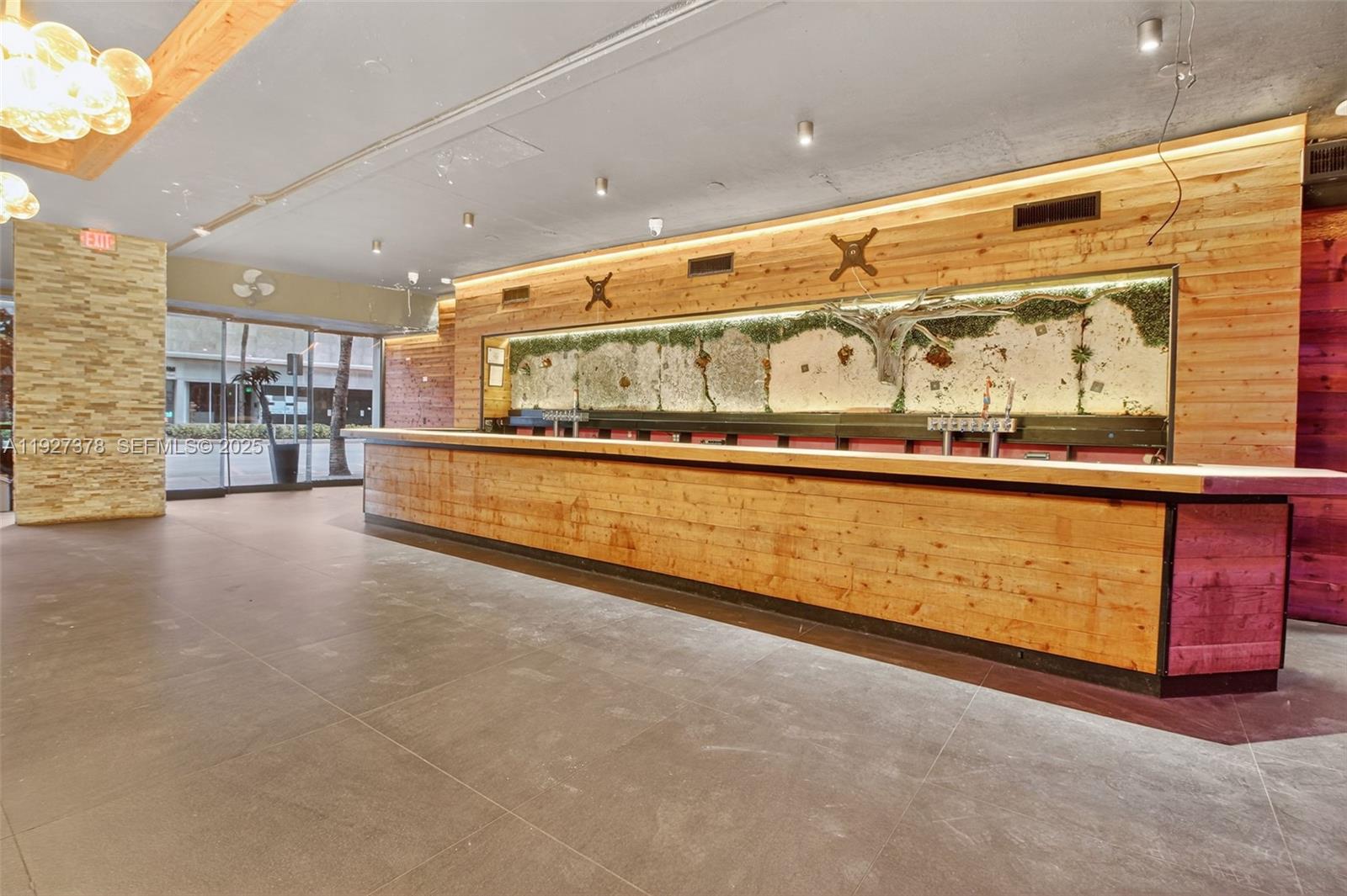 A commercial bar space features wood-paneled walls, a long counter, and large glass windows — 1216 Washington AVE, Miami Beach FL 33139, MIAMI BEACH, FL