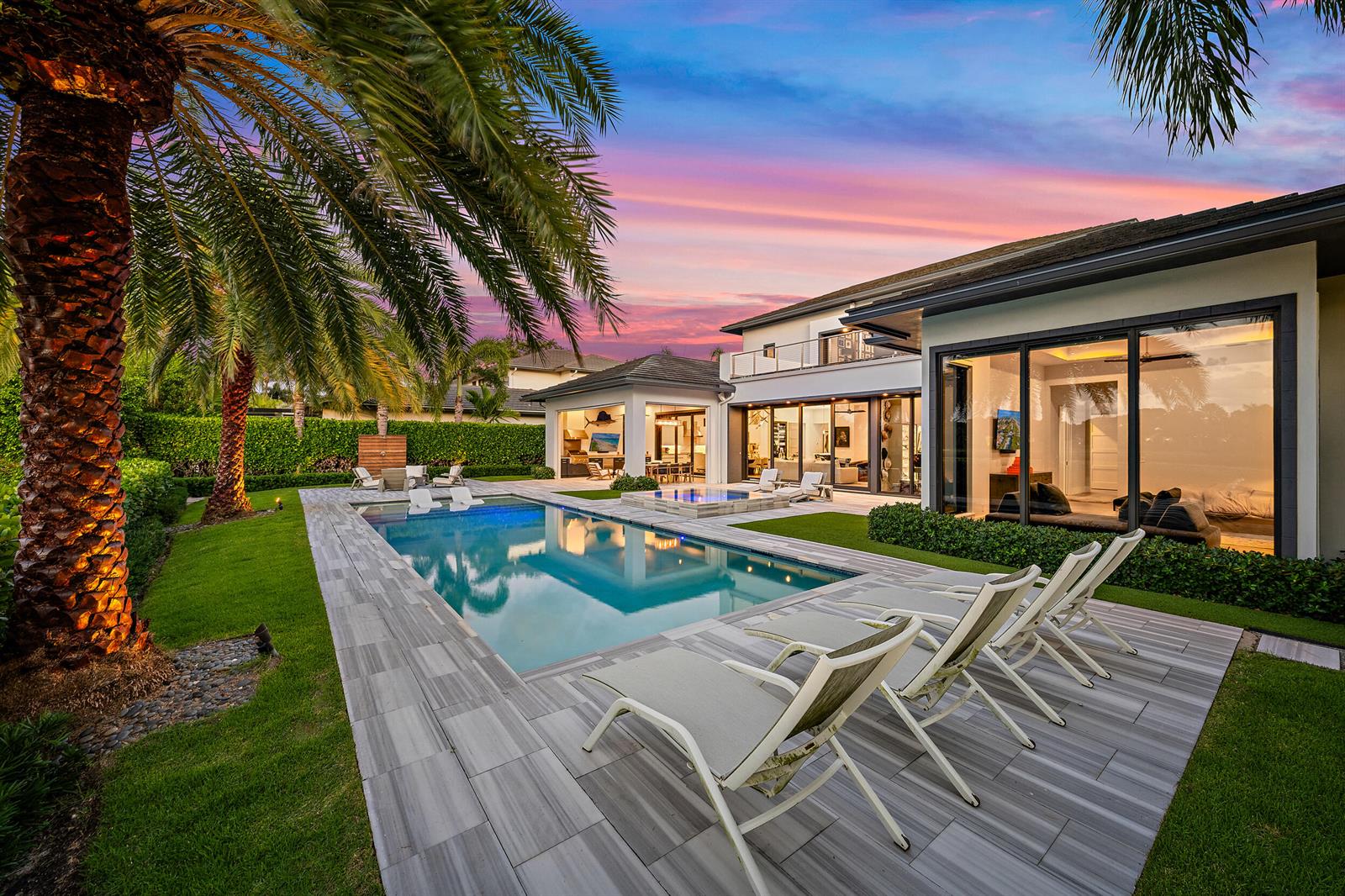 A modern house with a swimming pool, patio lounge chairs, and a sunset sky — 162 Commodore Drive, Jupiter FL 33477, JUPITER, FL