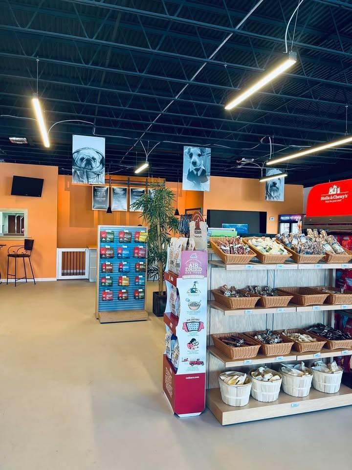 A retail pet store interior features shelves of pet food, hanging dog portraits, and orange walls — 1135 US Highway 1, Vero Beach FL 32960, VERO BEACH, FL
