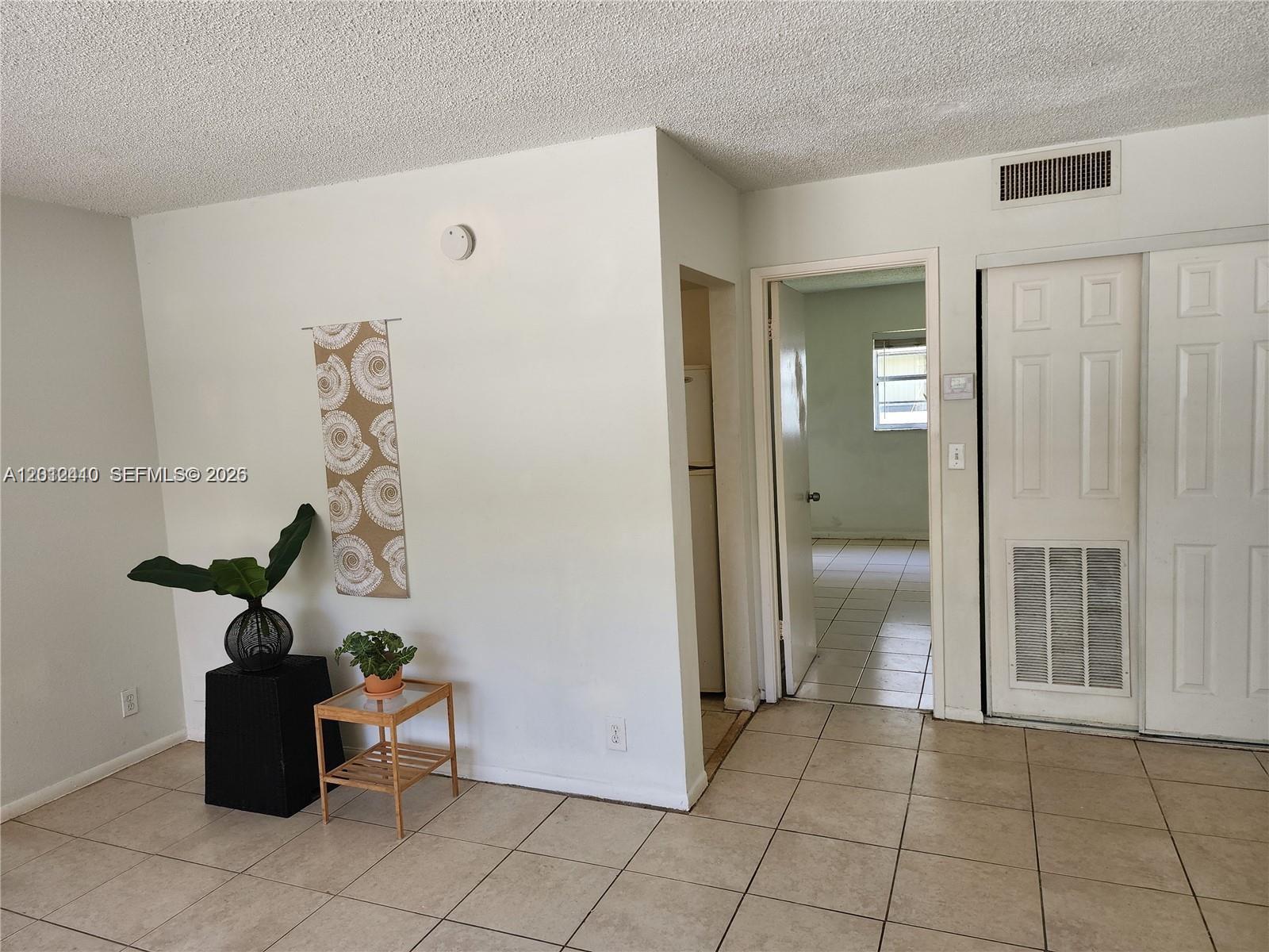 A room with tile flooring, a textured ceiling, a doorway, and a closet with louvers — 241 SE 9th Ave # 103, Pompano Beach FL 33060, POMPANO BEACH, FL