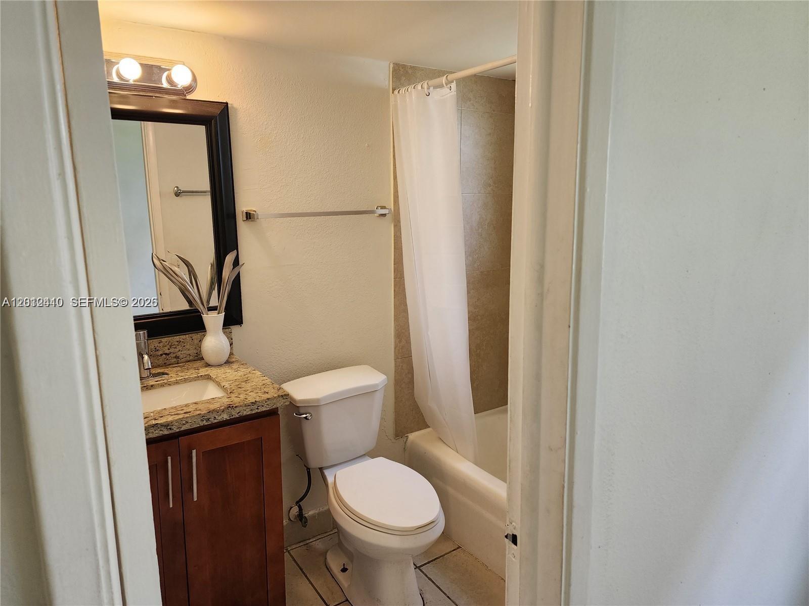 A bathroom features a granite-topped vanity, a white toilet, and a shower-tub combination — 241 SE 9th Ave # 103, Pompano Beach FL 33060, POMPANO BEACH, FL