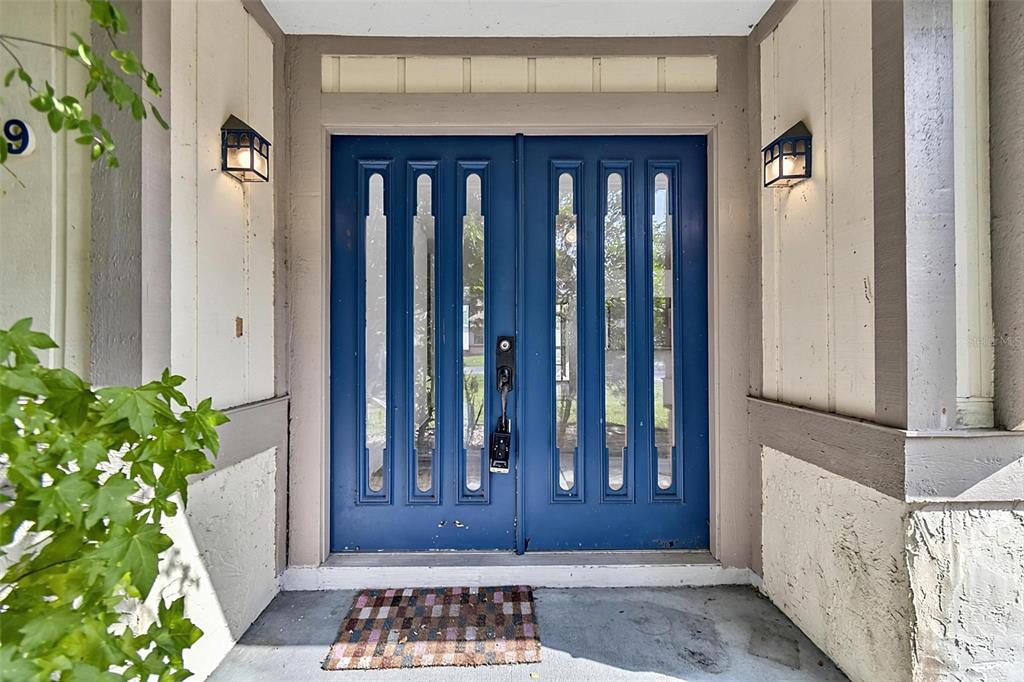 A blue double front door with vertical glass panels sits under a covered entryway — 19 BLACKBERRY PLACE, PALM COAST, FL