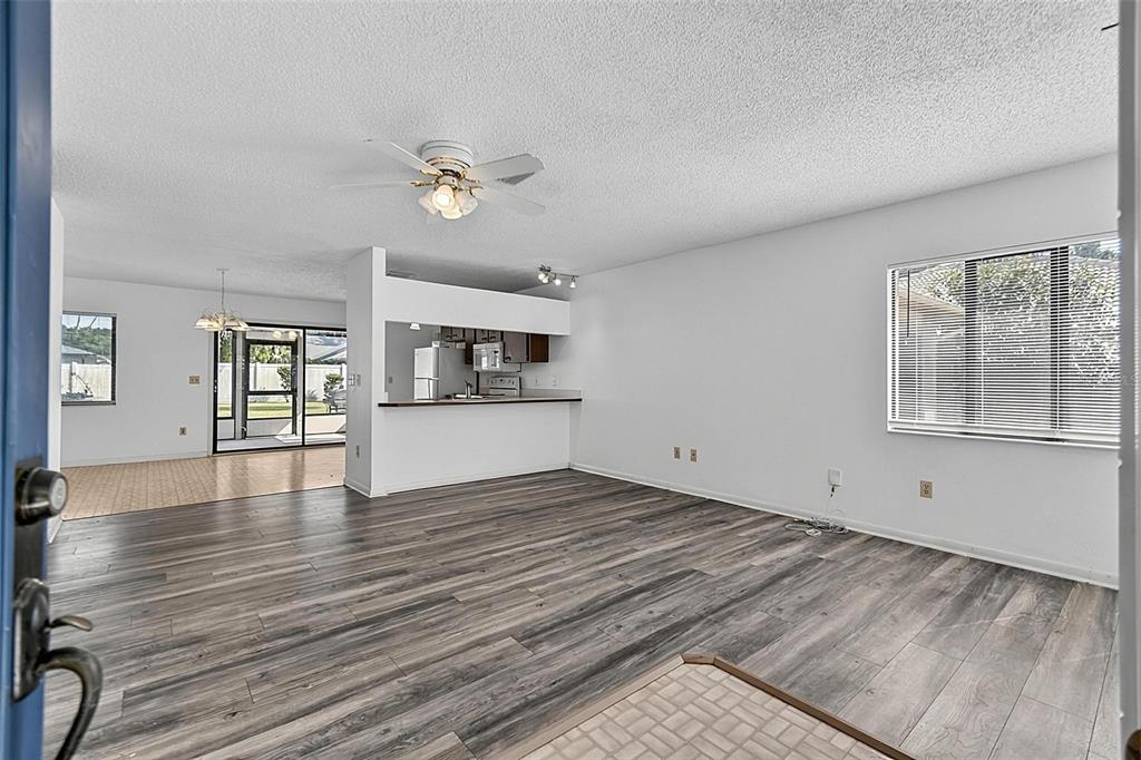 A living room with wood-look flooring, a ceiling fan, and an open kitchen pass-through — 19 BLACKBERRY PLACE, PALM COAST, FL