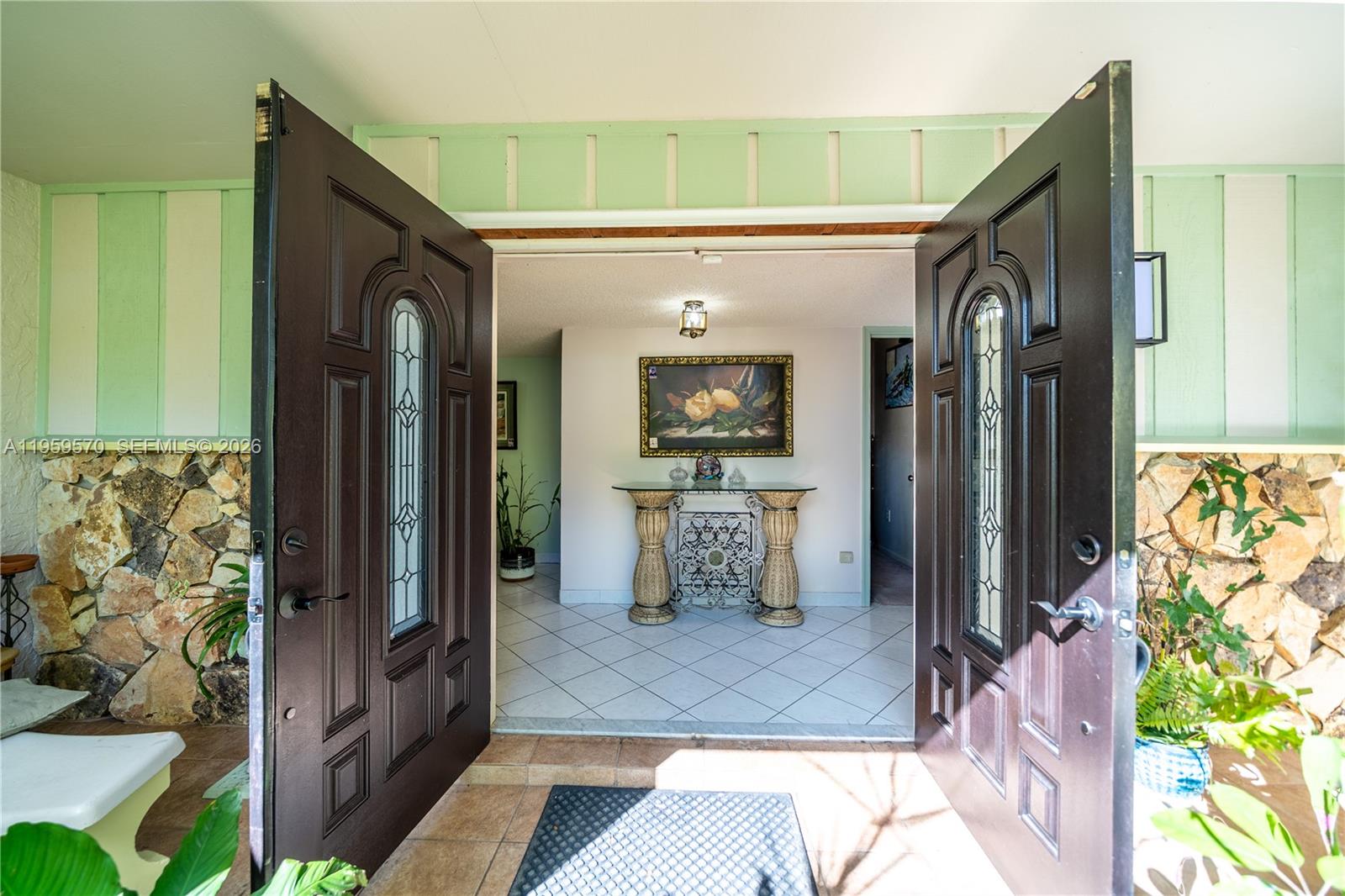 A view through open double doors into a tiled foyer with a decorative console table — 6337 SW 32nd St, Miramar FL 33023, MIRAMAR, FL