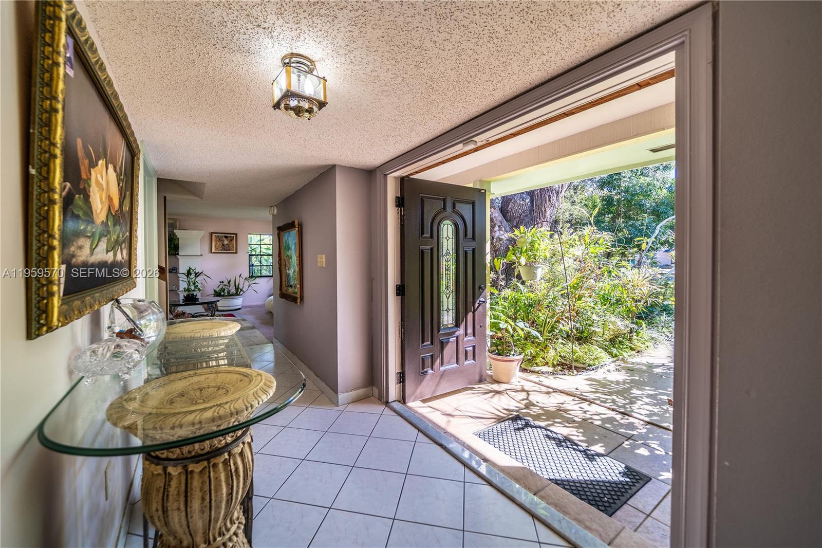 An entryway with tile floors leads to an open front door revealing a garden — 6337 SW 32nd St, Miramar FL 33023, MIRAMAR, FL