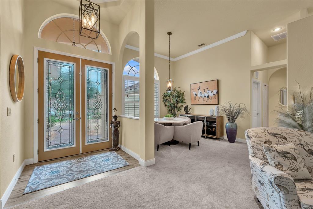 A bright foyer features double glass-paneled doors, a patterned rug, and an adjacent dining area — 5151 DELACROIX DRIVE, BROOKSVILLE, FL