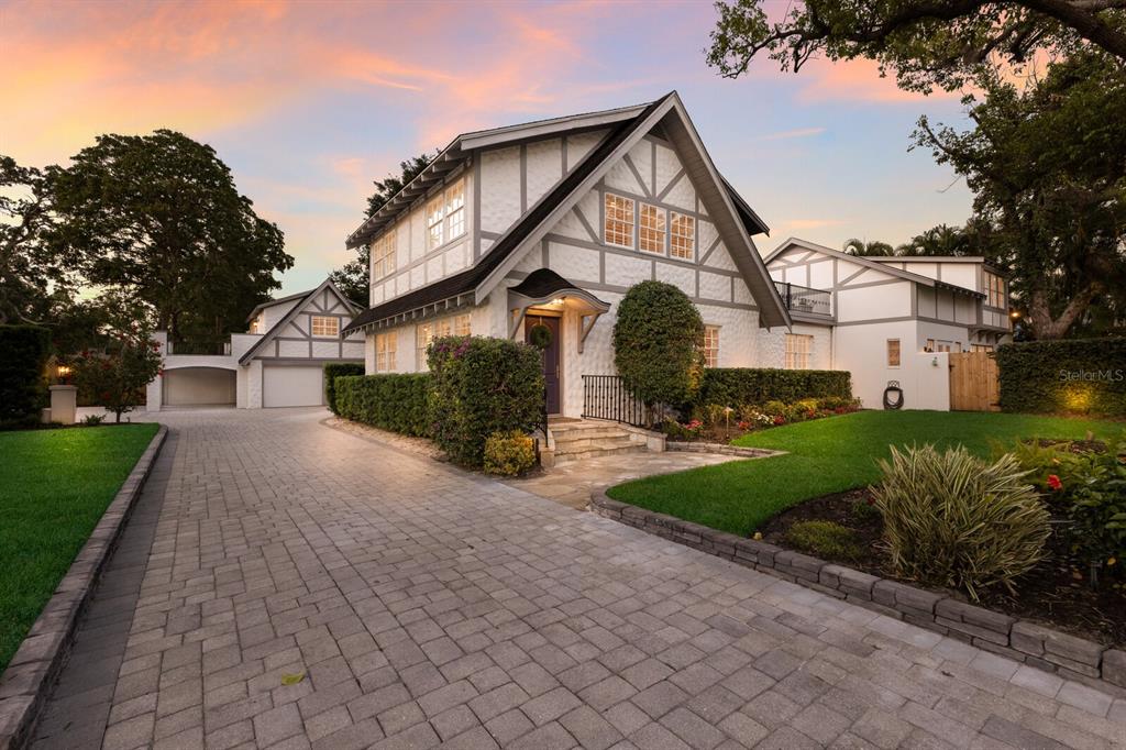 A two-story Tudor-style house with a paved driveway, manicured hedges, and a stone entryway — 1829 BOUGAINVILLEA STREET, SARASOTA, FL