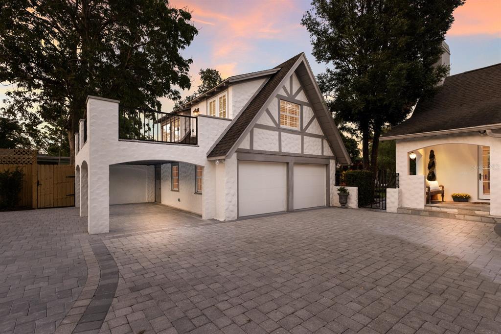 A two-story Tudor-style garage with a balcony and a paved driveway at dusk — 1829 BOUGAINVILLEA STREET, SARASOTA, FL