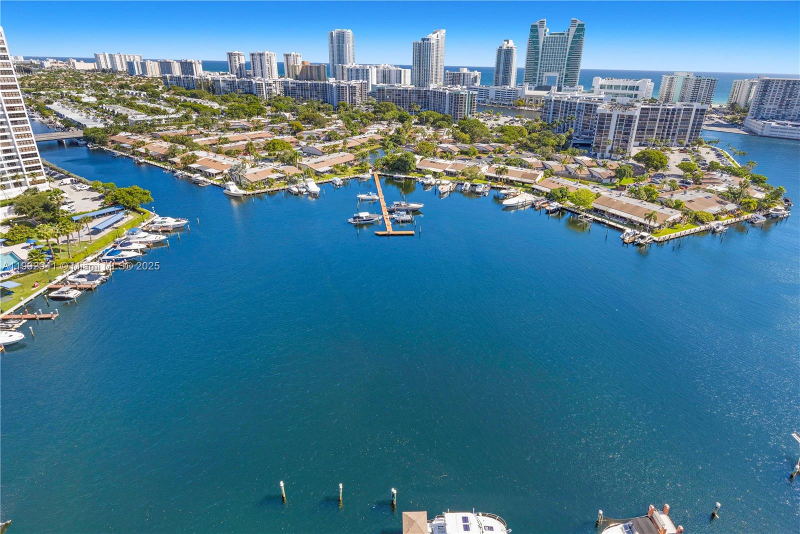 An aerial view shows a residential waterfront area with numerous boats docked along the shore — 300 Three Islands Blvd, Hallandale Beach FL 33009, HALLANDALE BEACH, FL