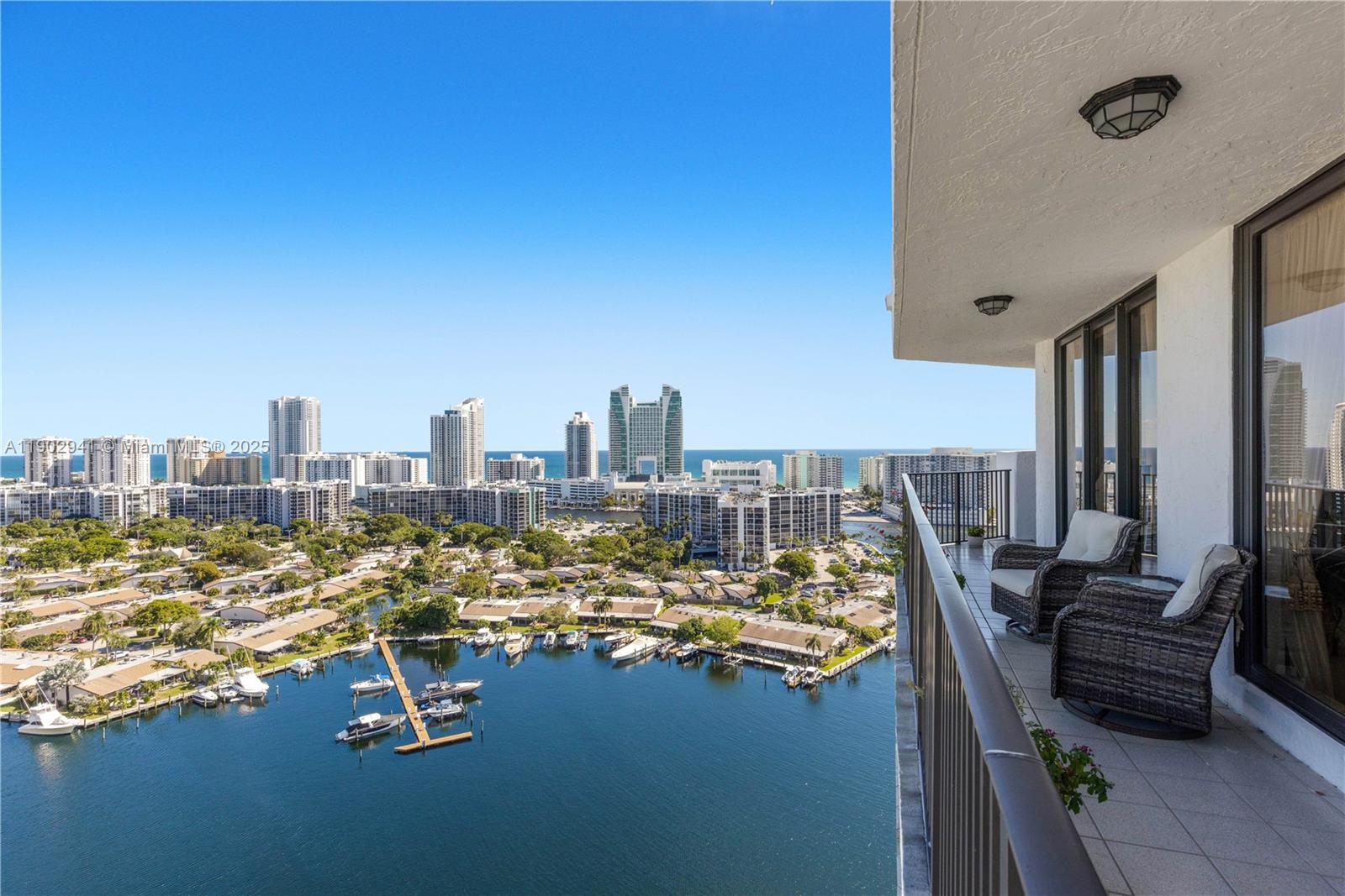 A high-rise balcony overlooks a marina, residential neighborhood, and distant coastal city skyline — 300 Three Islands Blvd, Hallandale Beach FL 33009, HALLANDALE BEACH, FL