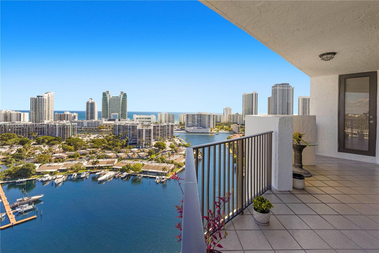 A high-rise balcony overlooks a bay, residential buildings, and a distant city skyline — 300 Three Islands Blvd, Hallandale Beach FL 33009, HALLANDALE BEACH, FL