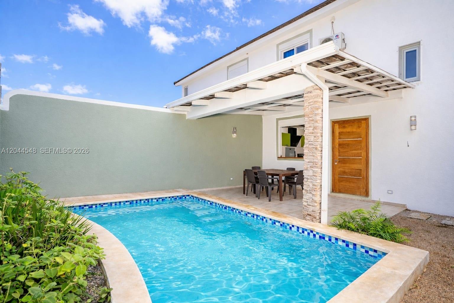 A backyard features a swimming pool, a covered patio with dining furniture, and a stone pillar — 01 Calle Mariano Vanderhorst, FL 32000, FL